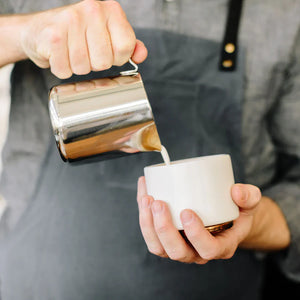 Barista a verter leite de jarro polido em aço inoxidável, parte dos Acessórios de Espresso e Jarro de Leite, tudo sobre café.