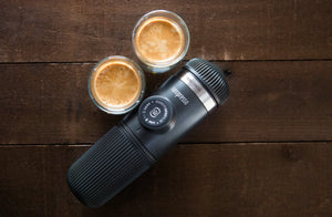 Máquina de espresso portátil com duas chávenas de espresso sobre superfície de madeira, de cafeteiras portáteis e equipamento de barista