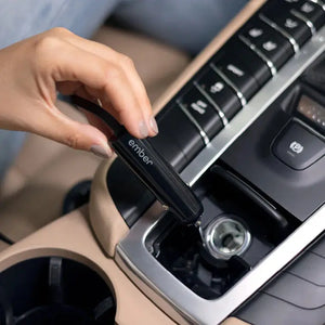 Mão a ligar carregador de carro para caneca elétrica Ember no isqueiro do carro para carregamento prático.